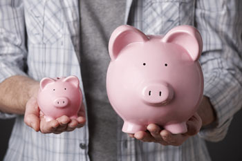 Jemand hält zwei unterschiedlich große Sparschweine in den Händen