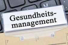 Nahaufnahme einer Akte, die mit "Gesundheitsmanagement" beschriftet ist und auf einer Tastatur liegt