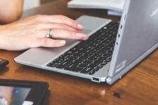 Die Hand einer Frau bedient einen Laptop an einem Bürotisch