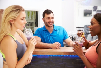 Fitnessfachwirte trinken Saftshakes an einer Saftbar