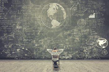 Ein Mann sitzt auf einem Stuhl vor einer riesigen mit Kreide beschriebenen Tafel