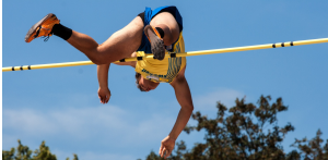 Sportstudent springt über eine Hochsprungstange