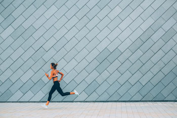 Junge Frau läuft vor grauer Wand