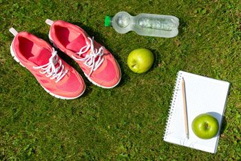 Sportschuhe, Notizblock und Wasserflasche auf Rasen