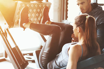 Trainer unterstützt Frau beim Trainieren 