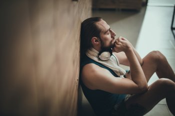 Sportler sitzt nachdenklich an eine Wand gelehnt 