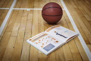 Handbuch für Basketball und Basketball liegen auf dem Boden einer Turnhalle